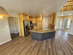 Kitchen featuring stainless steel appliances, kitchen peninsula, light stone countertops, backsplash, and dark hardwood / wood-style floors