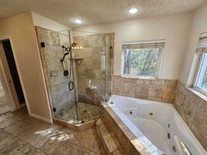 Bathroom with plus walk in shower, a wealth of natural light, and a textured ceiling