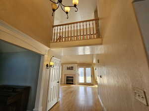 Corridor featuring a high ceiling, hardwood / wood-style floors, and a notable chandelier