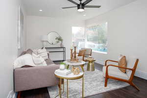 Living room with ceiling fan and dark wood-type flooring