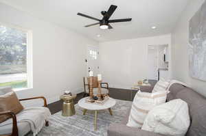 Living room with ceiling fan and hardwood / wood-style flooring