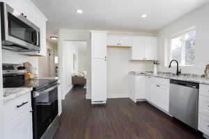 Kitchen featuring white cabinets, appliances with stainless steel finishes, and dark hardwood / wood-style floors