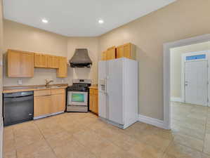 Kitchen featuring dishwasher, stainless steel range with gas cooktop, white fridge with ice dispenser, sink, and extractor fan.