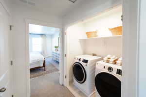 Washroom featuring light carpet and washing machine and dryer