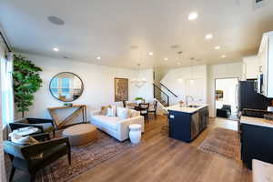 Living room with wood-type flooring, plenty of natural light, sink, and a chandelier