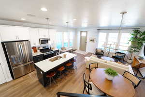 Kitchen with a wealth of natural light, white cabinets, appliances with stainless steel finishes, and decorative light fixtures