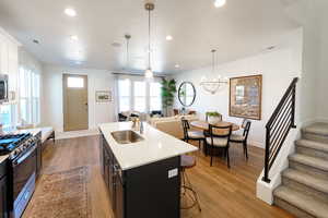 Kitchen featuring pendant lighting, stainless steel appliances, a center island with sink, hardwood / wood-style floors, and sink