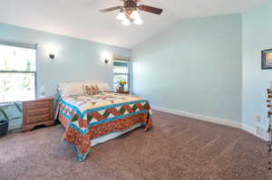 Carpeted bedroom featuring lofted ceiling and ceiling fan