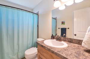 Bathroom with a shower with curtain, vanity, and toilet