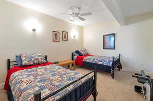 Bedroom featuring ceiling fan, light carpet, and beam ceiling