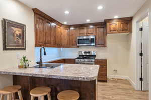 Kitchen featuring appliances with stainless steel finishes, sink, kitchen peninsula, and light hardwood / wood-style flooring