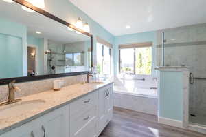 Bathroom with wood-type flooring, vanity, and separate shower and tub