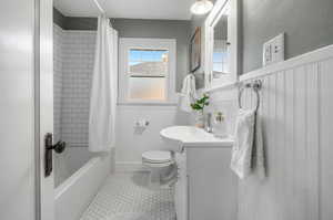 Recently remodeled full bathroom with vanity, toilet, shower / bath combo, built ins and patterned tile floors.