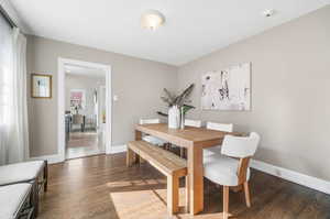 Large dining area with dark hardwood floors and large windows that bring in lots of natural light.