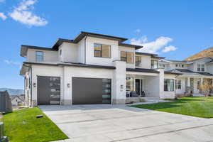 View of front of house with a mountain view, a front yard, and a garage