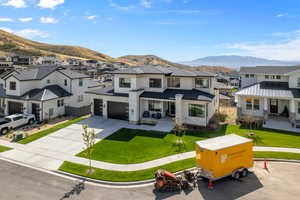 View of front of house with a garage, a front lawn, and a mountain view