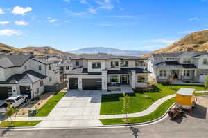 View of front facade with a mountain view, a front lawn, and a garage