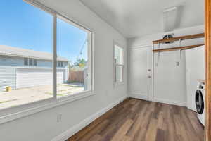 Laundry room featuring washer / dryer and dark hardwood / wood-style floors qnd view of garage