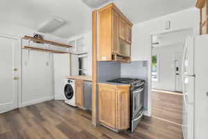 Kitchen with washer / clothes dryer, appliances with stainless steel finishes, and dark wood-type flooring