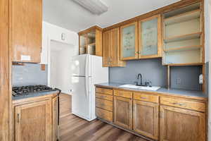 Kitchen with gas cooktop, dark hardwood / wood-style flooring, sink, and white fridge