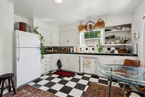 Kitchen with white cabinets, white refrigerator, tile countertops, and backsplash