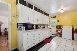 Kitchen with decorative backsplash, white cabinetry, sink, and light tile patterned floors