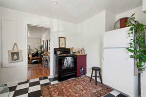 Kitchen featuring black / electric stove and white refrigerator