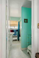 Bathroom with tile patterned flooring, toilet, and radiator heating unit