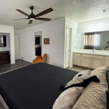 Bedroom featuring ensuite bathroom, ceiling fan, and a textured ceiling