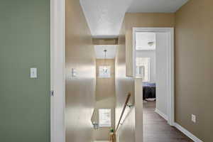 Corridor featuring a textured ceiling and hardwood / wood-style floors