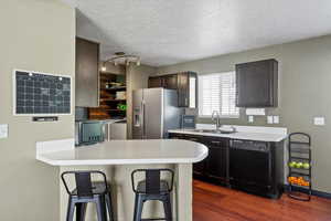 Kitchen featuring stainless steel fridge, sink, a textured ceiling, dishwasher, and washer and dryer