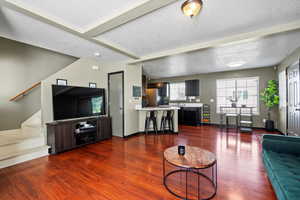 Living room featuring a textured ceiling, sink, and dark hardwood / wood-style flooring