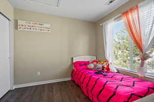 Bedroom with multiple windows, a textured ceiling, and dark wood-type flooring