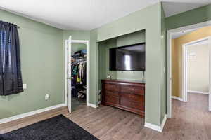 Bedroom with a textured ceiling, hardwood / wood-style flooring, and a closet