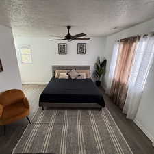 Bedroom featuring ceiling fan, wood-type flooring, and a textured ceiling