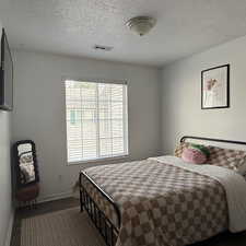 Bedroom featuring a textured ceiling and dark wood-type flooring