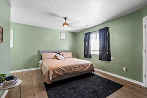 Bedroom featuring ceiling fan, hardwood / wood-style flooring, and a textured ceiling