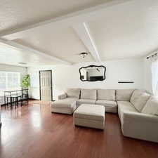 Living room with beamed ceiling, dark wood-type flooring, and a textured ceiling