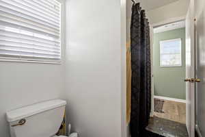 Bathroom with a textured ceiling, hardwood / wood-style floors, toilet, and a shower with shower curtain