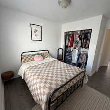 Bedroom with wood-type flooring, a textured ceiling, and a closet