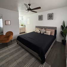 Bedroom with a textured ceiling, multiple windows, ceiling fan, and dark hardwood / wood-style floors