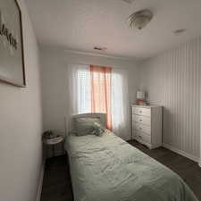 Bedroom with a textured ceiling and dark hardwood / wood-style flooring