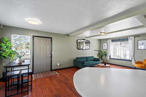 Interior space with a textured ceiling, a healthy amount of sunlight, and dark hardwood / wood-style flooring