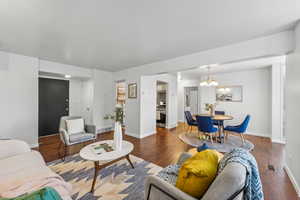 Living room featuring an inviting chandelier and dark laminate flooring open to the kitchen.