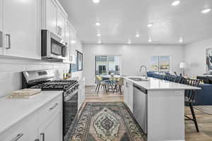 Kitchen featuring white cabinets, sink, a kitchen island with sink, stainless steel appliances, and a breakfast bar area *Photo is of an existing home of the same layout. Colors for listed home could vary*