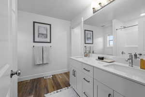 Bathroom featuring a shower, vanity, and hardwood / wood-style flooring *Photo is of an existing home of the same layout. Colors for listed home could vary*