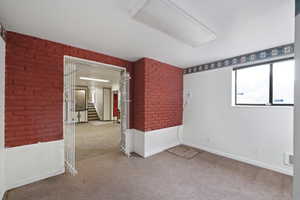 Carpeted spare room with brick wall