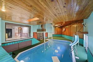 View of pool featuring a water slide, a skylight, and a diving board