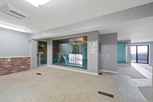 Interior space with a textured ceiling, carpet, and brick wall