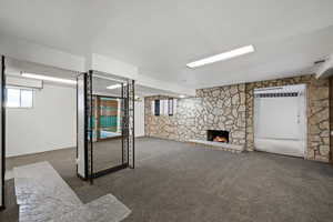 Basement with a stone fireplace and dark colored carpet